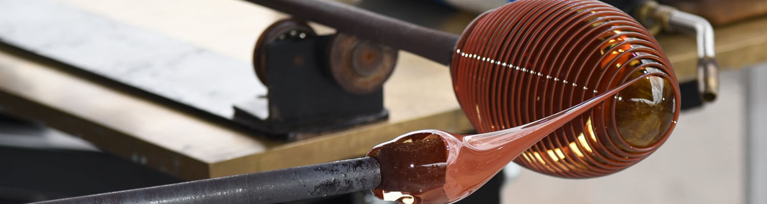 close up of red round glass being shaped