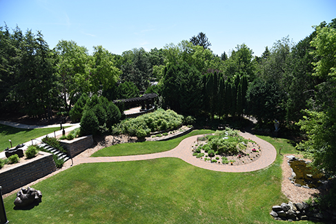 A view from the rooftop shows the Museum sculpture garden's green grass, plantings, sculpture, and brick pathways.