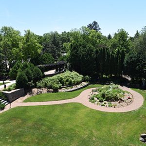 A view from the rooftop shows the Museum sculpture garden's green grass, plantings, sculpture, and brick pathways.