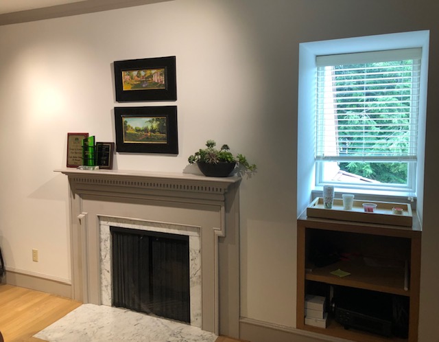This image shows a room with a window to the left of a fireplace