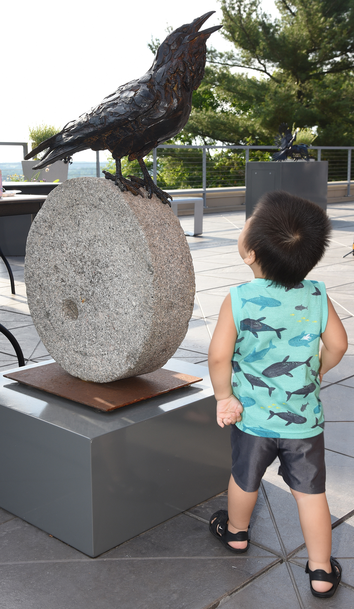 A young boy looks upward at a large raven sculpture in the museum's Rooftop Sculpture Garden