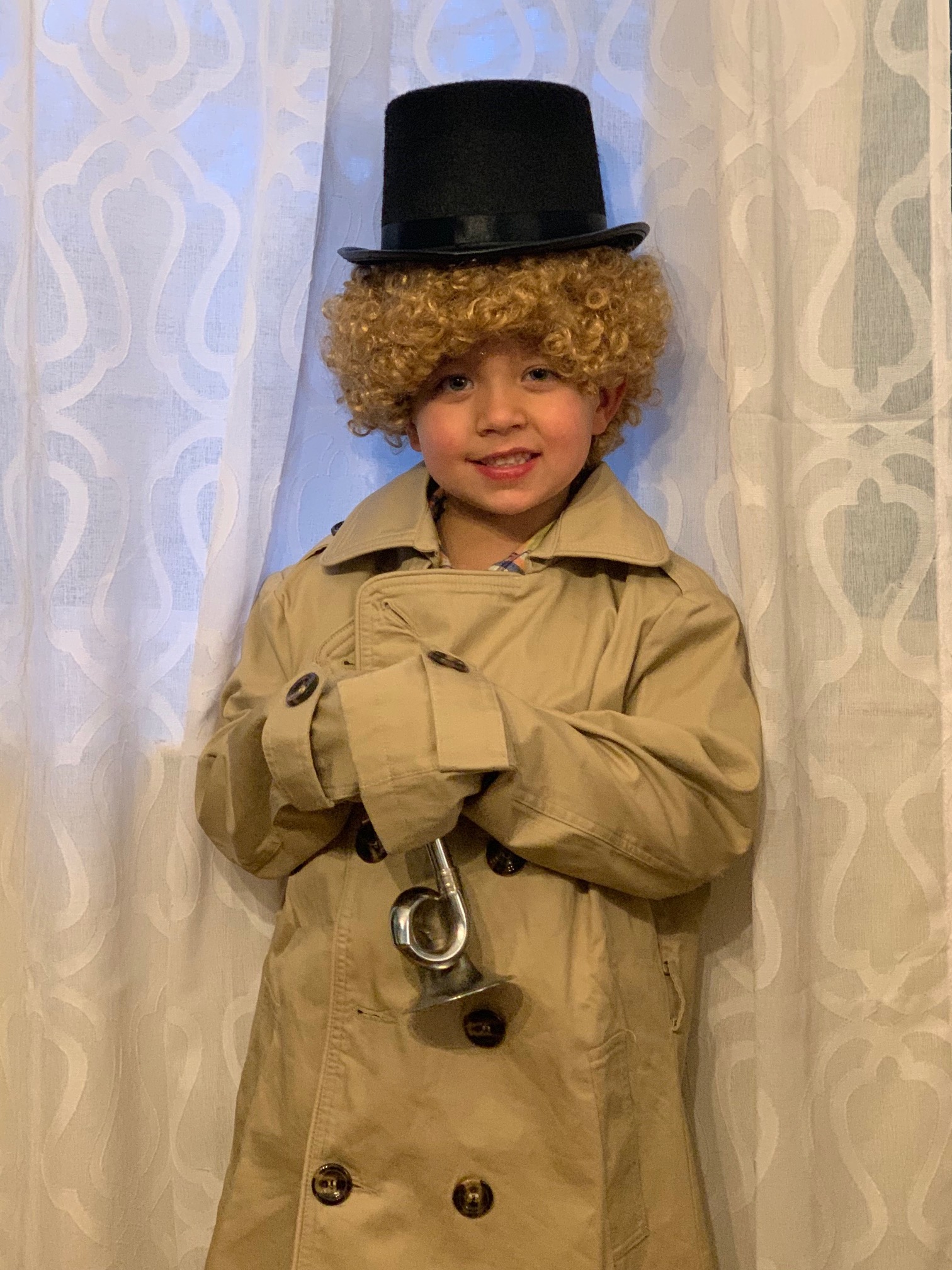 This photo shows a young boy dressed up as Harpo Marx, complete with trench coat, top hat, and blonde wig