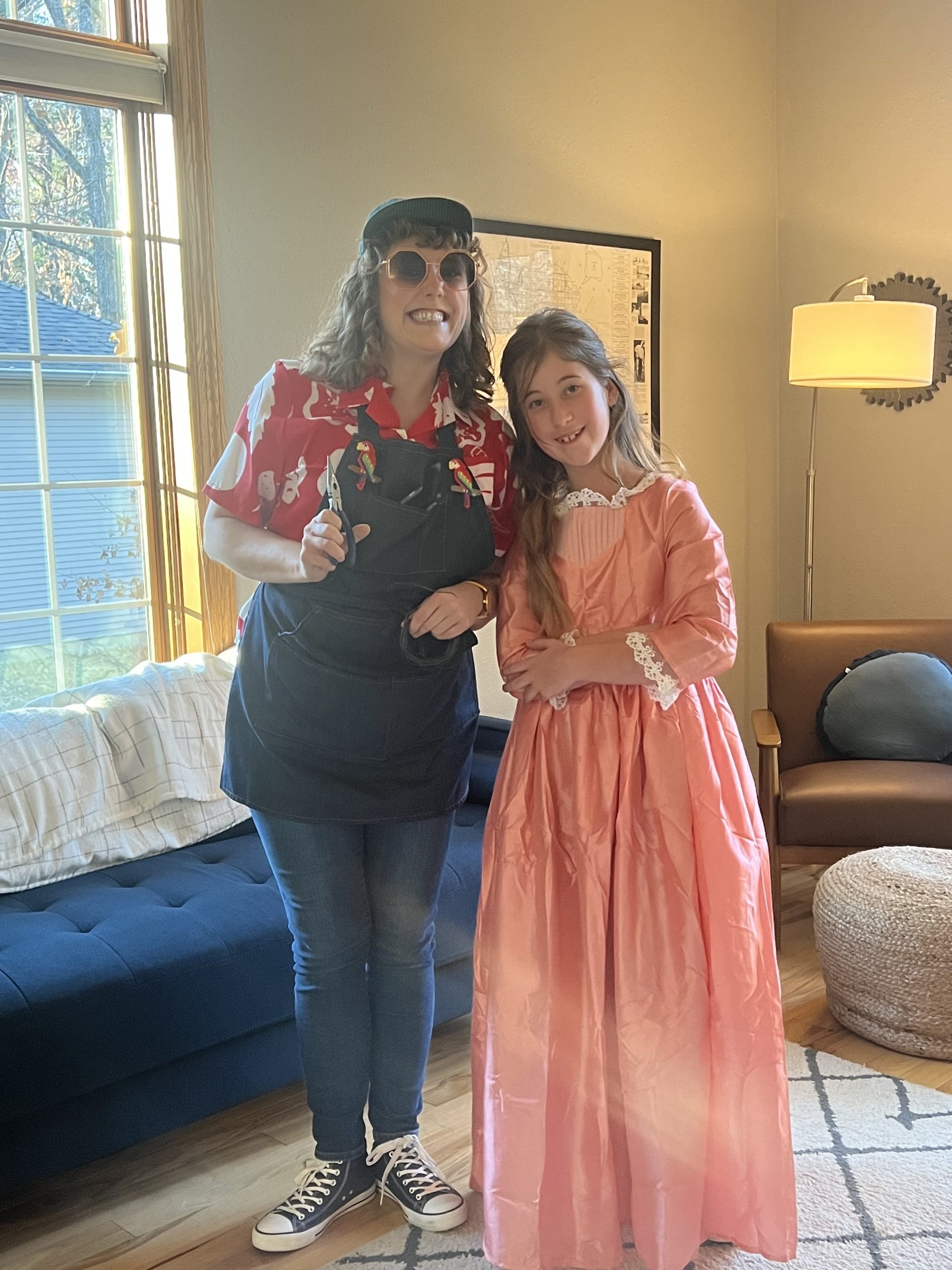 This photo shows Catie Anderson dressed as sculptor Tom Hill with hat, sunglasses, fun shoes, and holding wire next to a young girl dressed as Angelica Schuyler, in a fancy dress