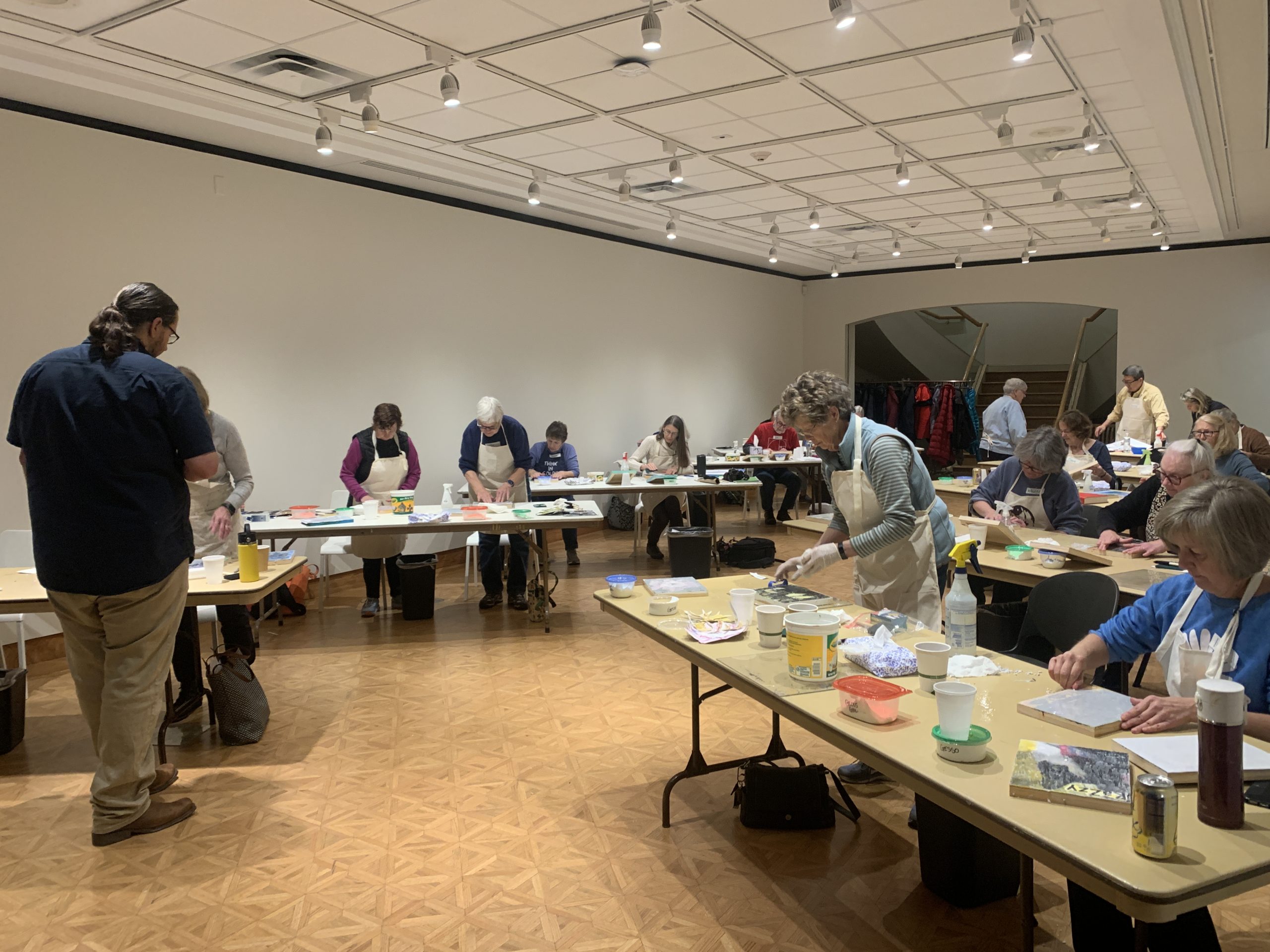 The Museum's lower level gallery filled with tables, art materials, and workshop participants creating their mixed-media artworks.