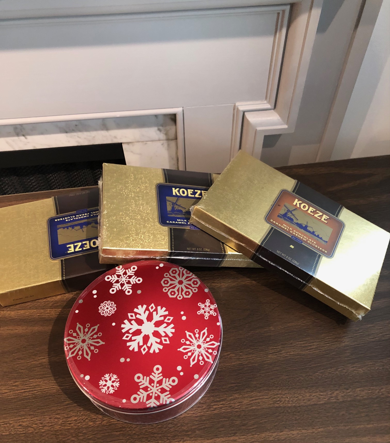 This image shows three boxes of candy surrounding a tin of peanut brittle