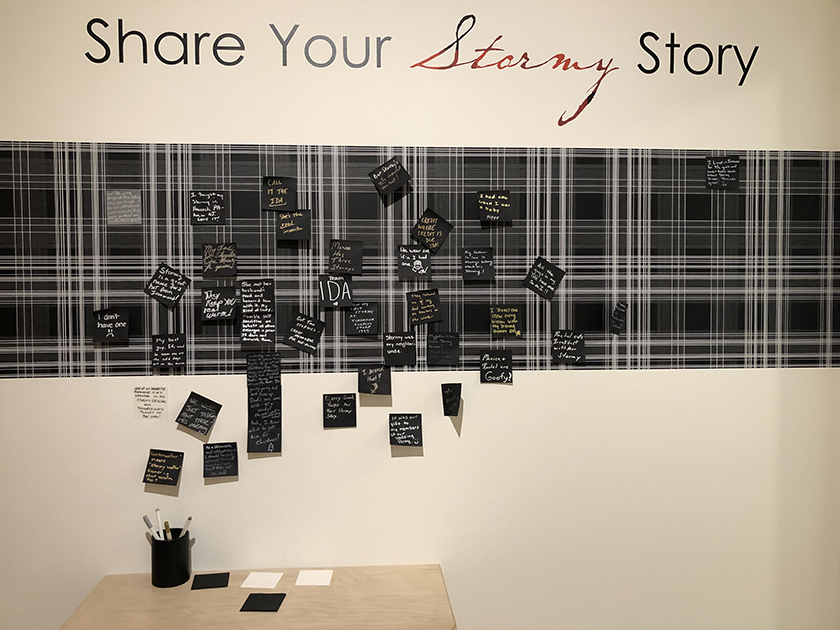 A "Share Your Stormy Story" museum wall where visitors post their comments on small black squares of paper