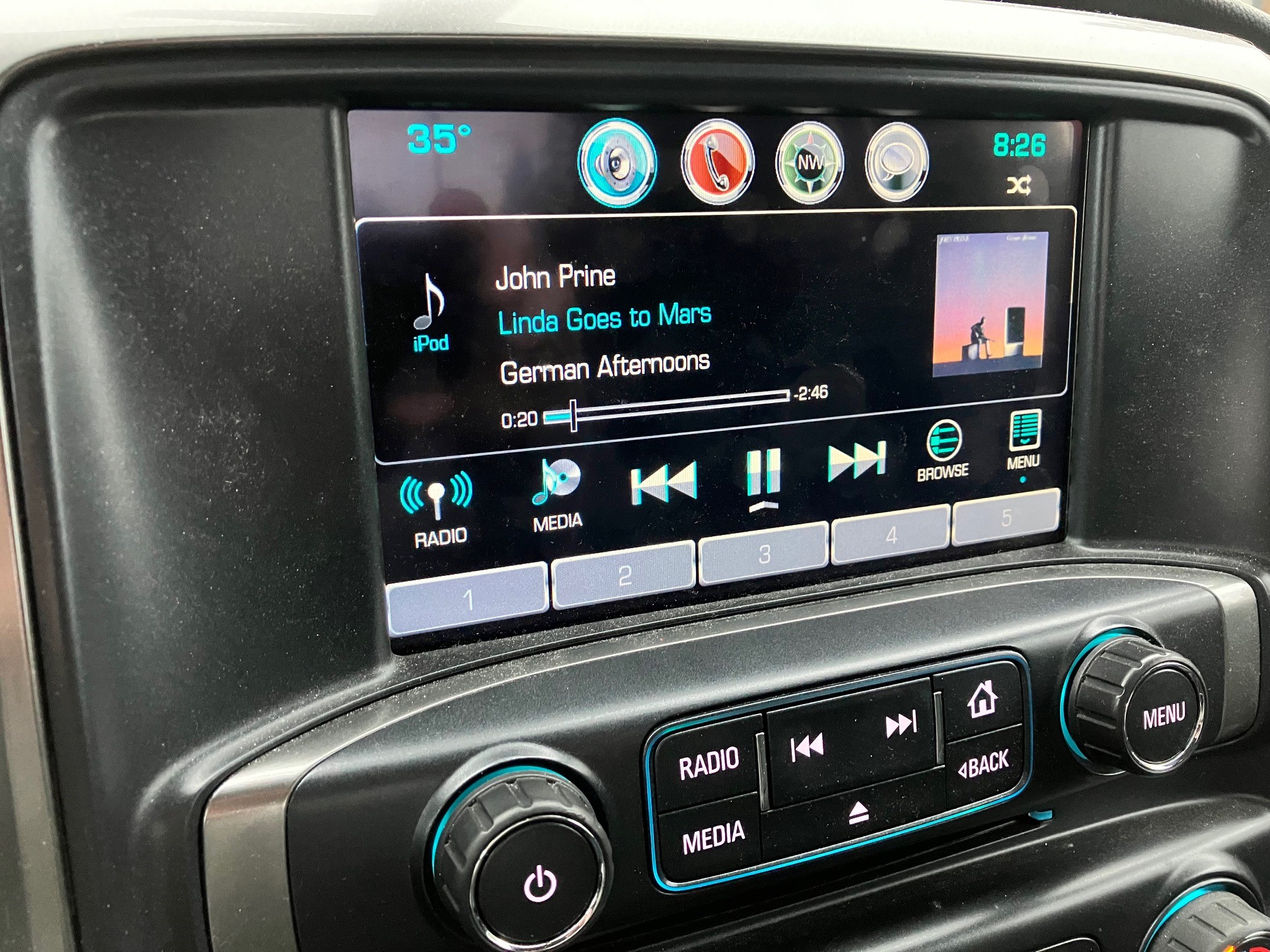 This photo shows the dashboard of a truck with a John Prine song playing