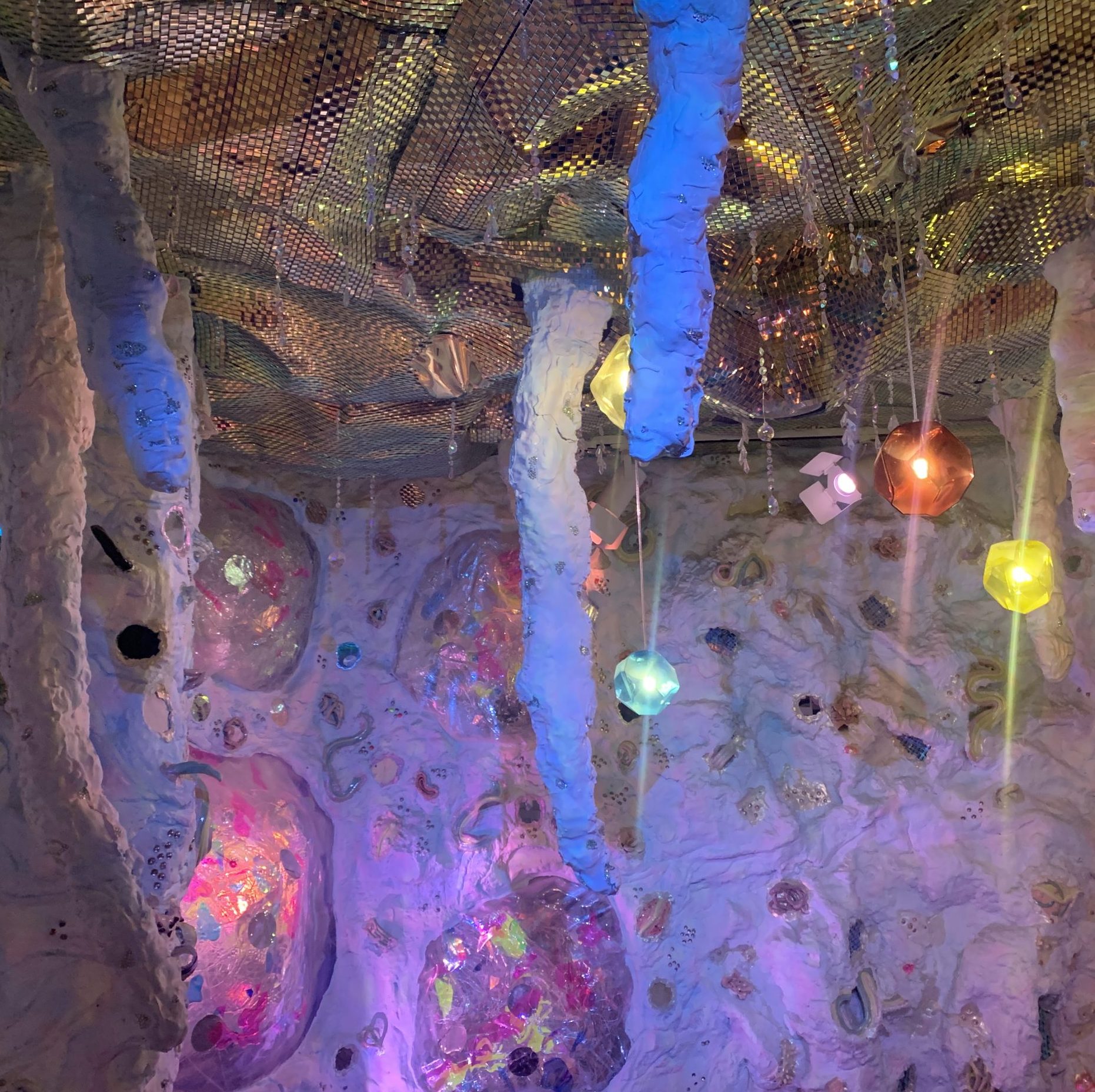 An immersive installation at Meow Wolf that appears like a cave with colorful gemstones
