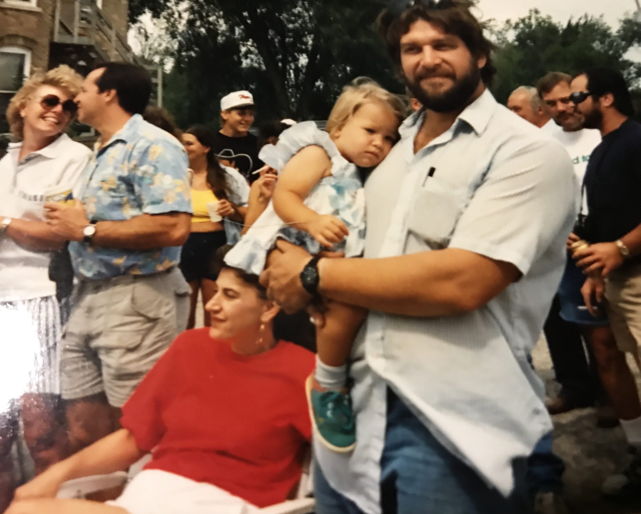 A father holds his one-year-old daughter next to the mother who wears a red shirt