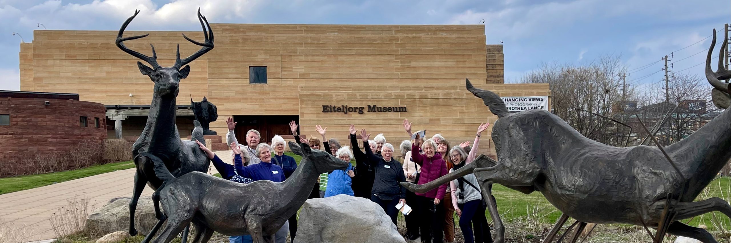 Travelers stand in front of the Eitaljorg Museum waving at the camera