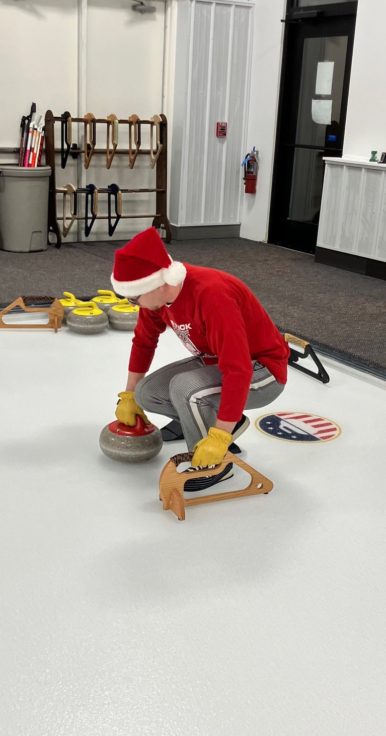 This image shows Museum Graphic Designer / Multimedia Specialist Daniel Knoedler getting ready to throw a curling stone