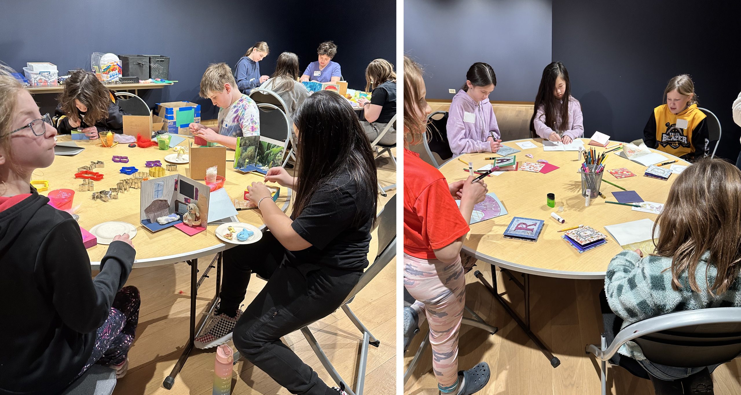 Students sit in a gallery space with navy blue walls working on needle felting, diorama creations, and explosion book illustrations