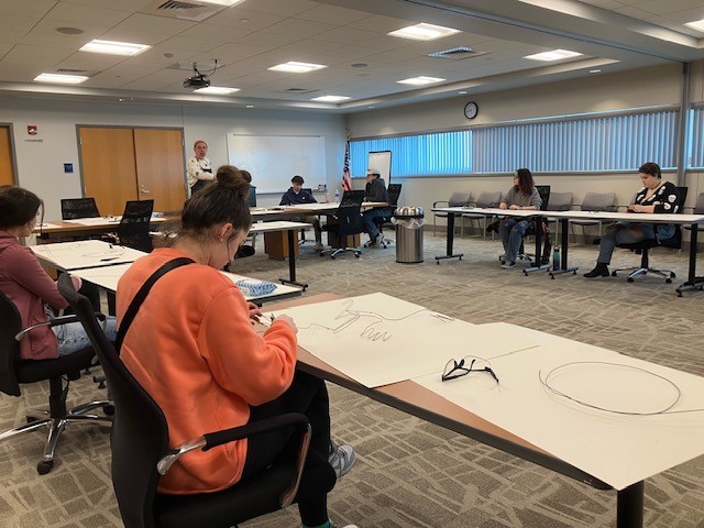 This image shows Tom Hill instructing high school students from Mosinee High School in how to form a wire bird