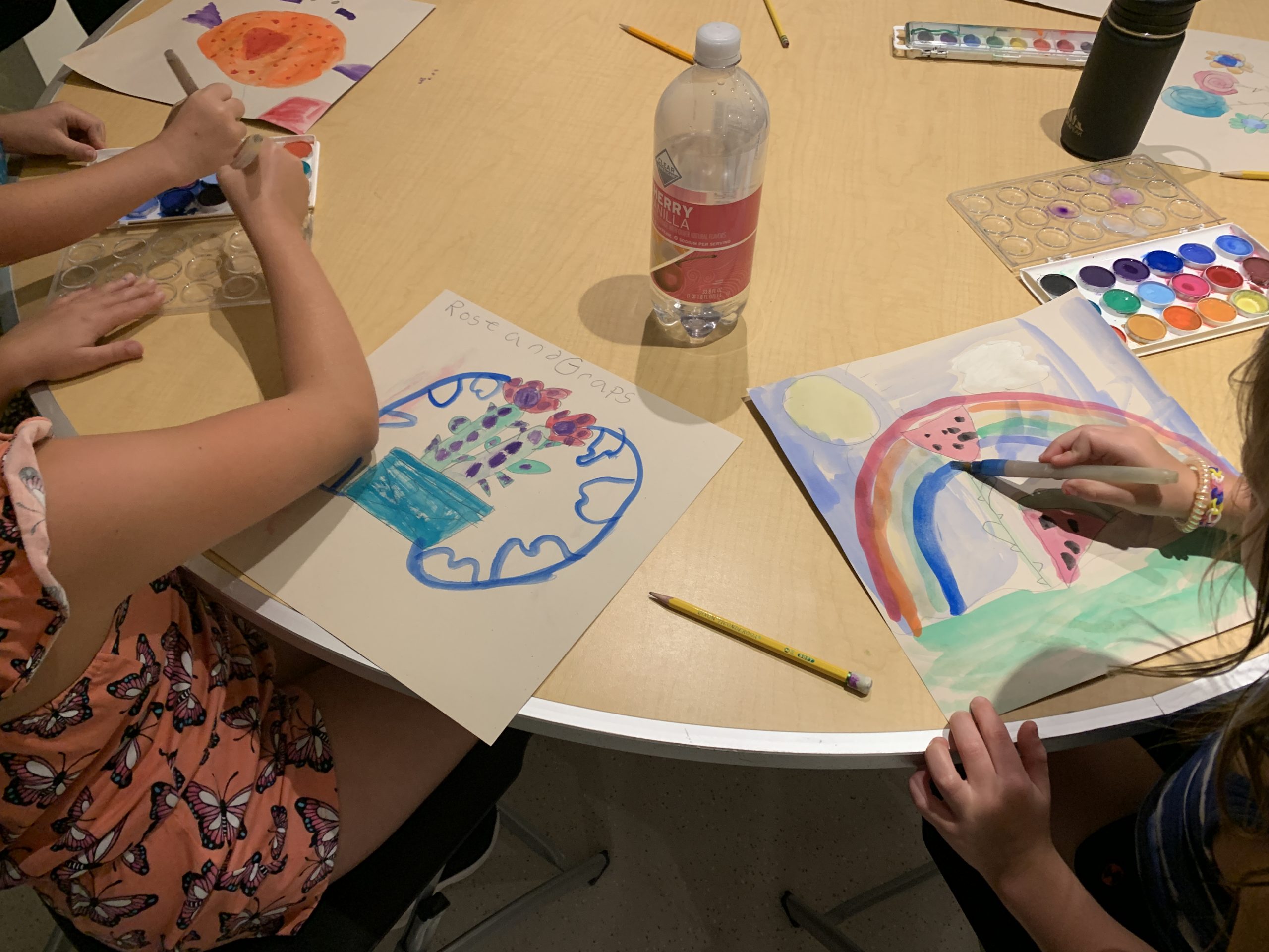 Children's hands working on their own watercolor paintings.  