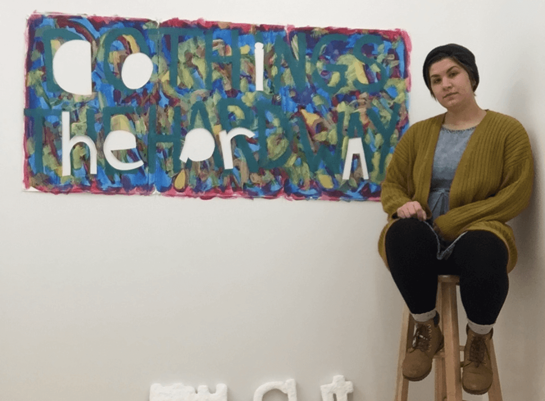 Rachel sitting next to an artwork in her studio space during the 2019 artist residency at Vermont Studio Center