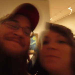 a blurry image of two people's faces close up. Between their heads you can see a small portion of van Gogh's Starry Night