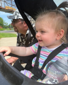 A baby smiling while she looks at animals at the zoo