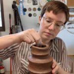 Headshot of Artist in Residence, Kate Marotz, as she works on a ceramic vase.